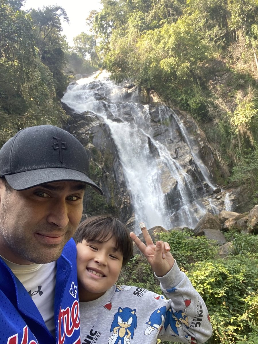 Ben and his son hiking together outdoors by a natural waterfall