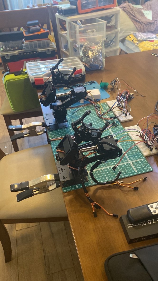 Two articulated robotic arms wired to breadboards on maker table