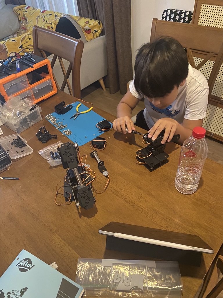Son assembling DIY robotic arm with tools and motors