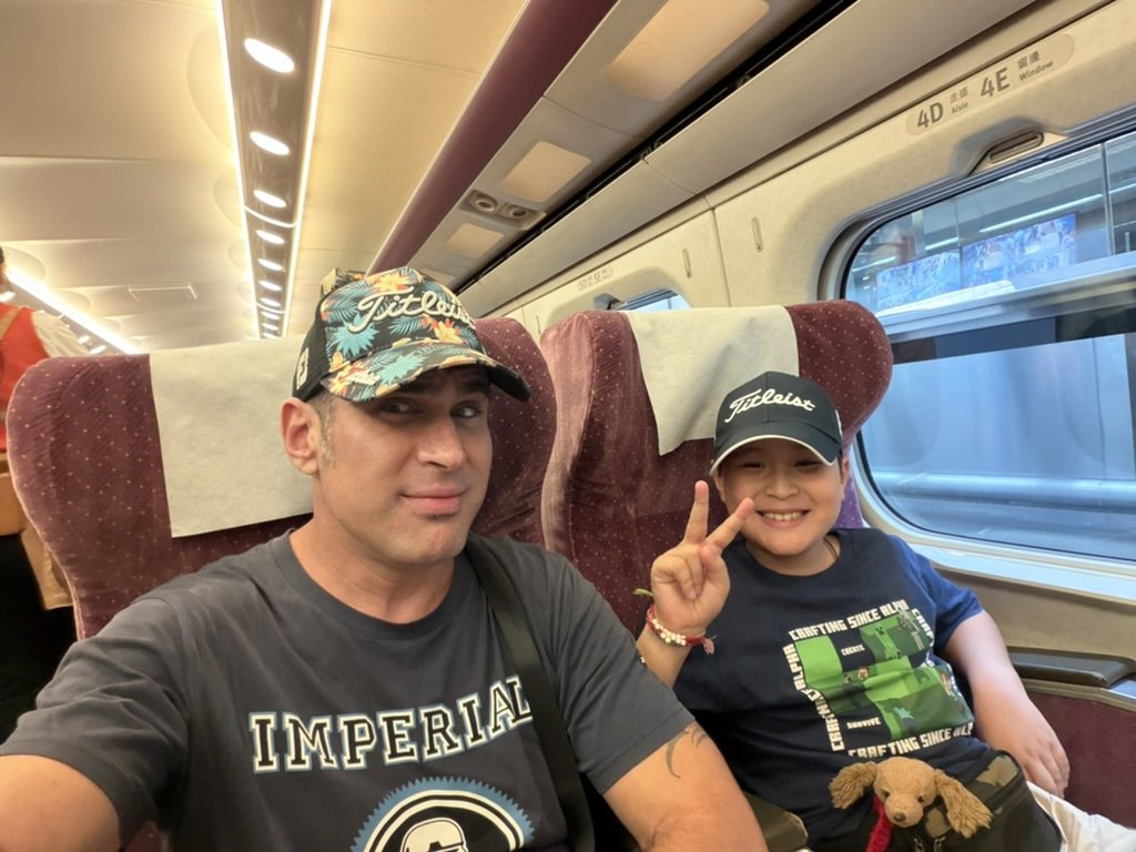 Ben and his son on Taiwan High Speed Rail in Titleist caps and Minecraft shirt
